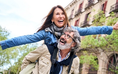 mulher de braços abertos sorrindo junto com um homem em uma cidade turística