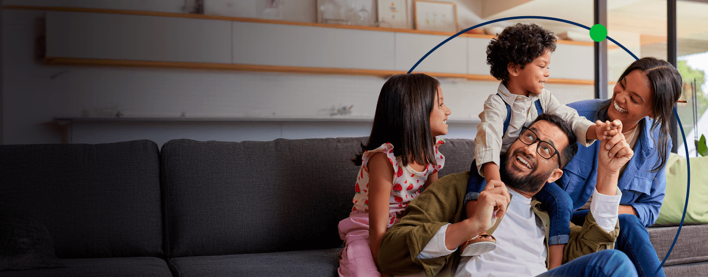 Família feliz brincando e sorrindo juntos em casa, evidenciando um momento de diversão e conexão emocional entre pais e filhos.