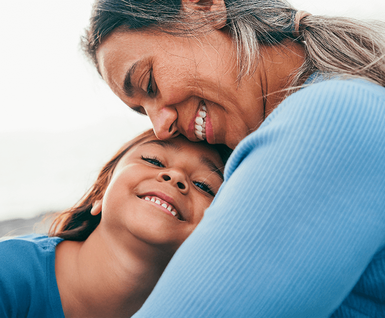Mãe e filha sorrindo e se abraçando, demonstrando amor e alegria em um momento afetuoso e feliz.
