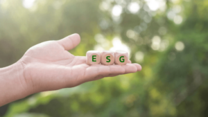 Imagem mostrando uma mão segurando três blocos com as letras E, S e G, destacando a importância de práticas de ESG para sustentabilidade ambiental, social e de governança.