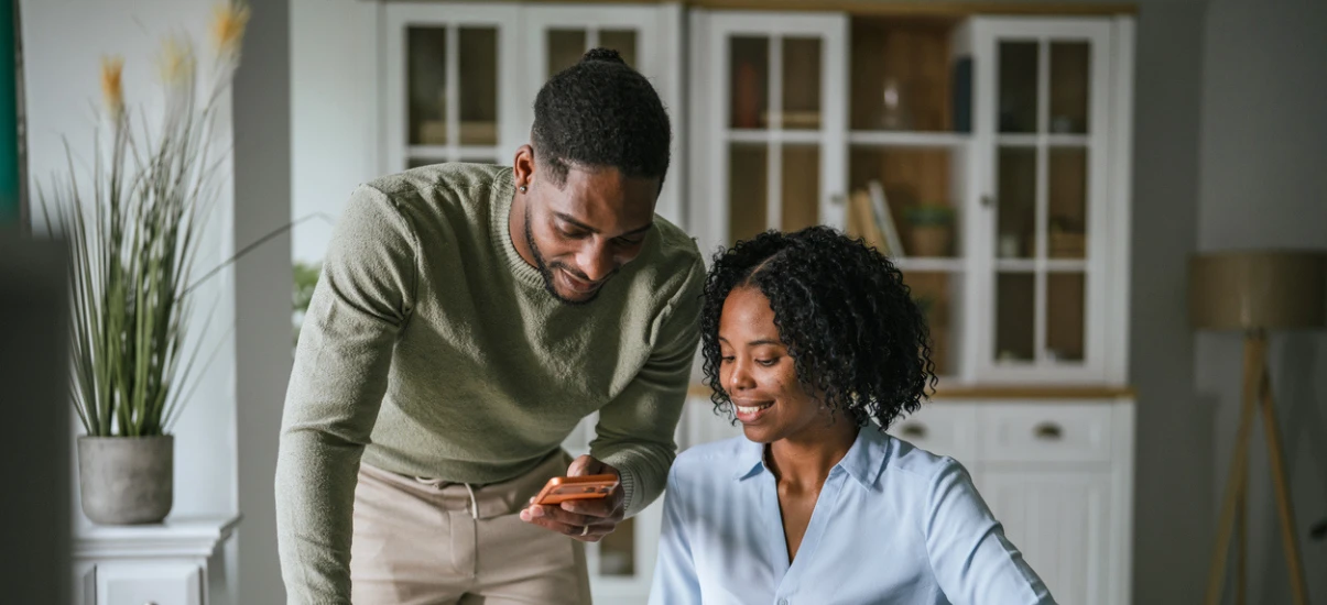 como quitar dívidas descricao-pessoa-mostrando-celular-para-colega-sorrindo