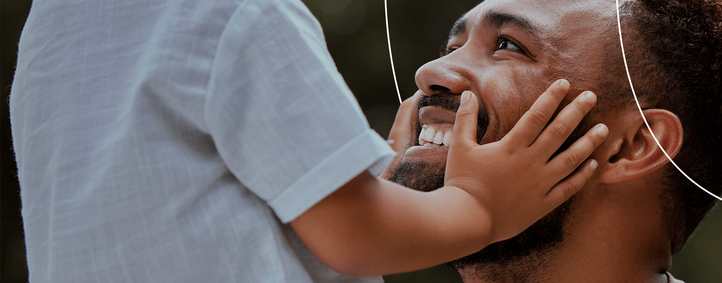 mão de criança no rosto de um pai sorrindo para ela